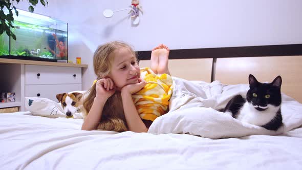 Girl 1011 Years Lying on Bed with Pets Cat and Dog Smiling Watching TV