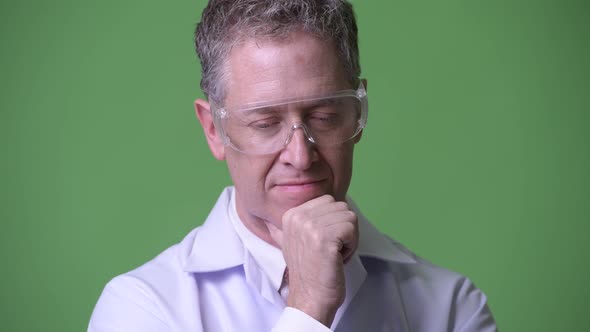 Serious Mature Man Doctor with Protective Glasses Thinking
