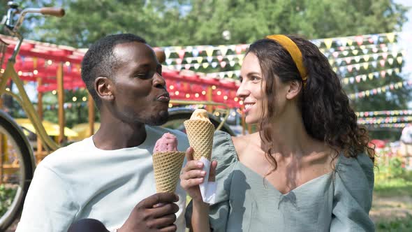 Black Man and Brunette Eat Organic Icecream on Grass Lawn alt