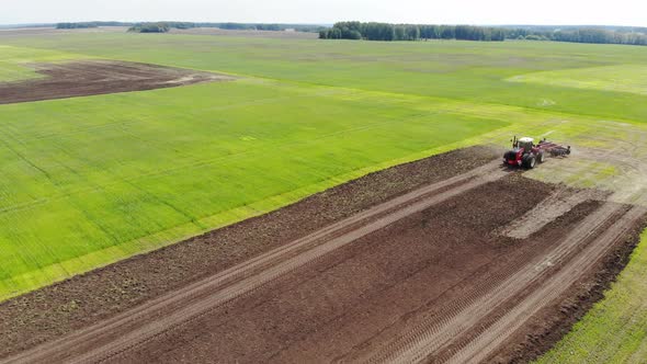 Red Harvester Drives Across Field and Plows Earth alt