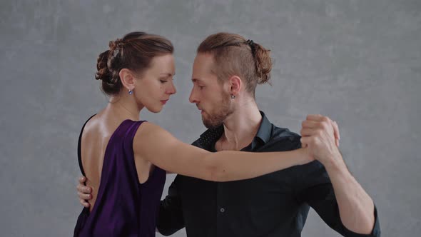 Man and Woman are Sensually Dancing a Tango in Grey Studio