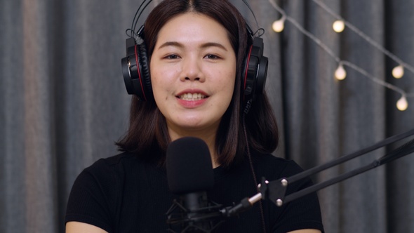 Asian woman influencer recording a vlog using podcast microphone.