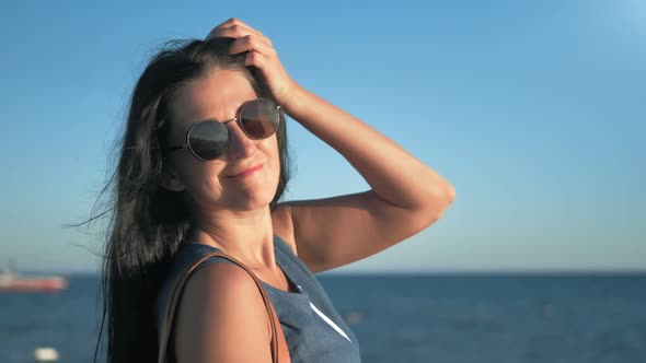 Relaxed Happy Girl in Trendy Sunglasses Flirting at Sunrise Surrounded By Natural Coast and Sky alt