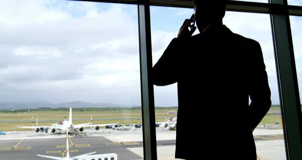 Businessman talking on mobile phone at airport alt