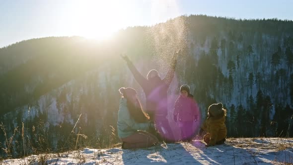 A Young Happy Family is Having Fun Playing in the Snow at Sunset