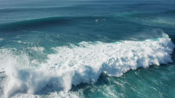 Crushing waves at sunny day; blue water, thick seafoam, natural abstract pattern, sea texture