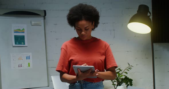 Young Woman Uses a Digital Tablet in Office Then Looking Into the Camera alt