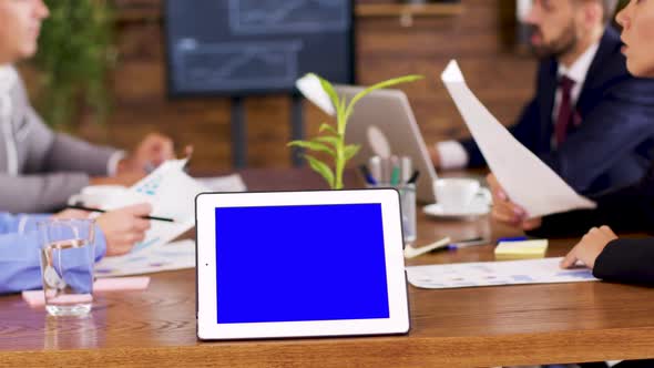 Tablet with Blue Screen on the Table in the Conference Room alt