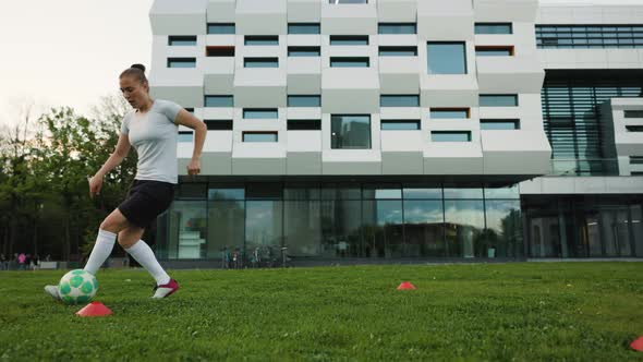 Woman Soccer Player Trains on the Grass Field in the the Evening Park a Freestyler Leads the Ball
