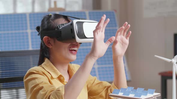 Woman Working With A Model Of Small House Roof Solar Panel Wearing Vr And Showing Touching Gesture alt