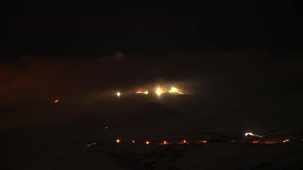 8K Night lights of Antennas on Top of Snowy Mountain in Fog and Clouds