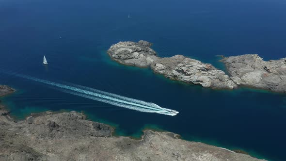 Aerial View of Boat Sailing Along Rocky Sea Coast alt