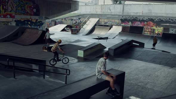 Sporty Teenagers Spending Time Together at Urban Skate Park with Graffiti alt