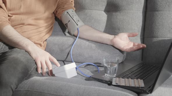 A Man  the Internet for how to use a Blood Pressure Monitor and Measures his own Blood Pressure. alt