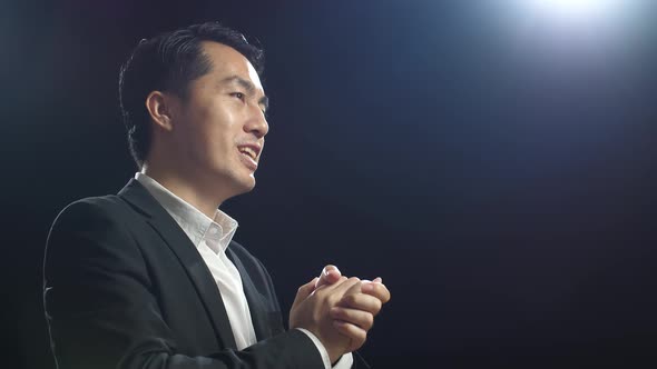 Close Up Side View Of Asian Speaker Man In Business Suit Showing Index Fingers Up While Speaking alt