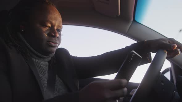 Young African American Black Man Using Smartphone and Sending Messages While Driving alt