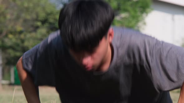 Healthy young man doing a pushup in a grass field. Concept of dynamic exercise and cardio training alt