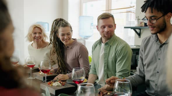 Diverse Group of Adults Chatting and Laughing Sitting at Table with Food and Drinks alt