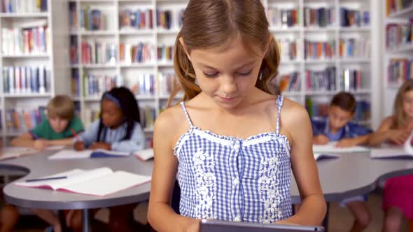 Schoolgirl using digital tablet in library alt