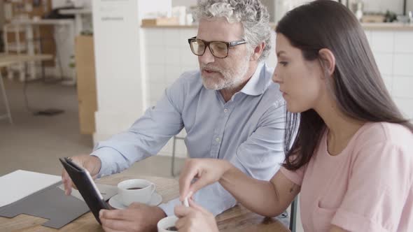 Bearded CEO Pointing at Tablet Screen with Finger and Showing alt