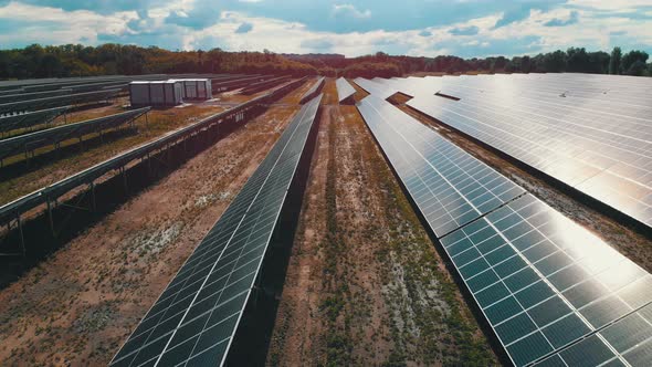 Aerial View of Solar Power Station. Panels Stand in a Row on Green Field. Summer alt