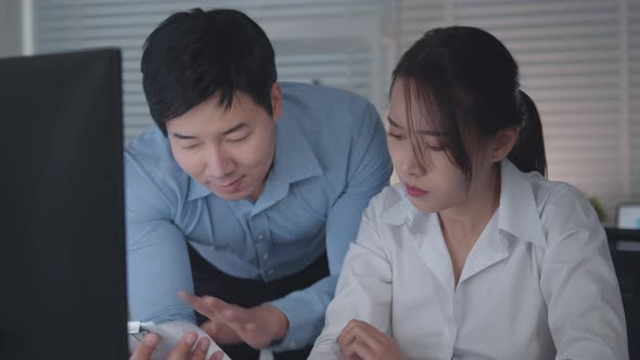 Asian Businessman and Businesswoman looking at desktop computer screen discussing  a business