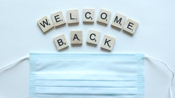 phrase welcome back composed from wooden letters covered by mask alt