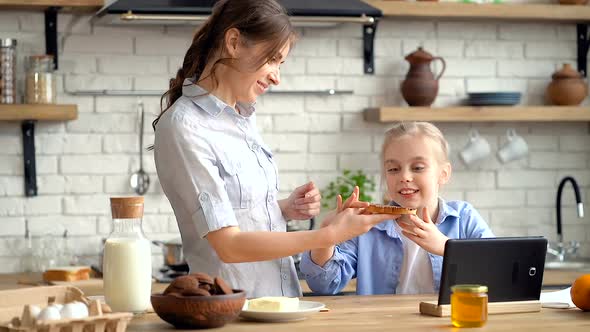 Happy mother and daughter at the kitchen. Breakfast time.