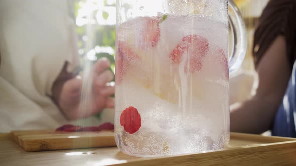 Woman Make Drink with Lemon and Strawberry Slices in Jug