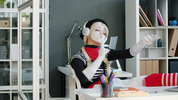 Funny Mime Businesswoman Enjoying Music Through Headphones Playing Invisible Violin in Office alt