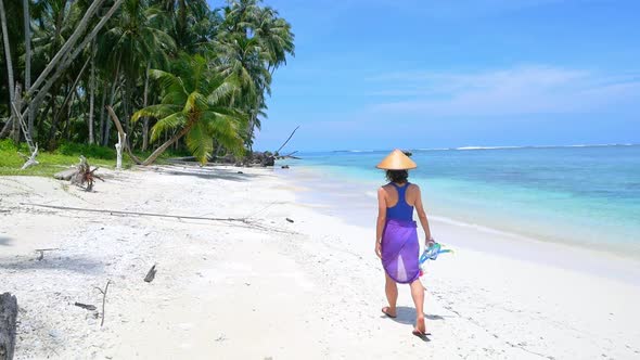 Slow motion: woman holding snorkeling gear walking on sunny tropical beach caribbean sea palm trees alt