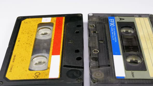 Two Audio Cassettes Rotate on White Background alt