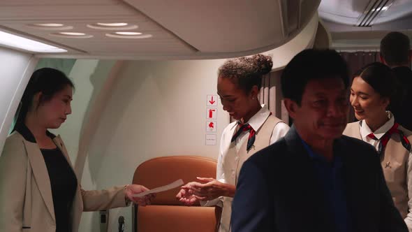 Multiracial passengers boarding airplane and checking seats boarding pass by flight attendants