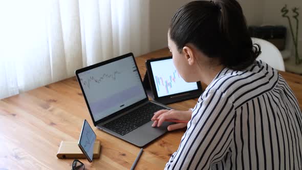 Woman taking notes by examining cryptocurrency charts in detail.