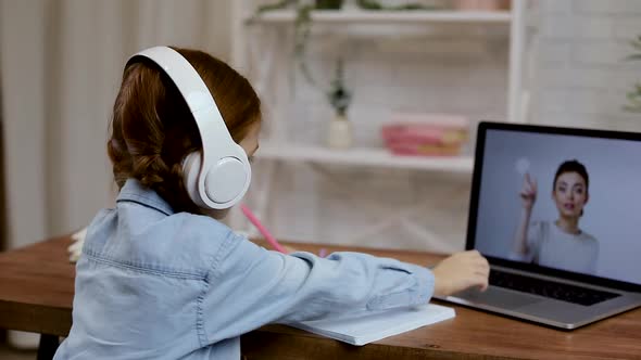 Little Child Girl Using Laptop for Doing School Tasks at Home and Writing Notes