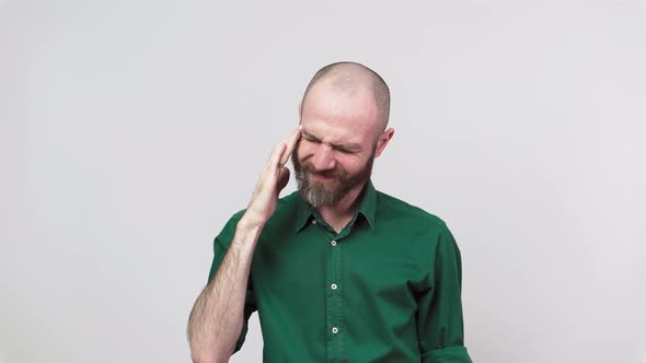 Portrait of bearded man having headache isolated over white background. Sick unhappy man