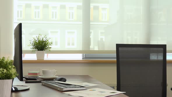 The interior of an empty office with a desk and a computer alt