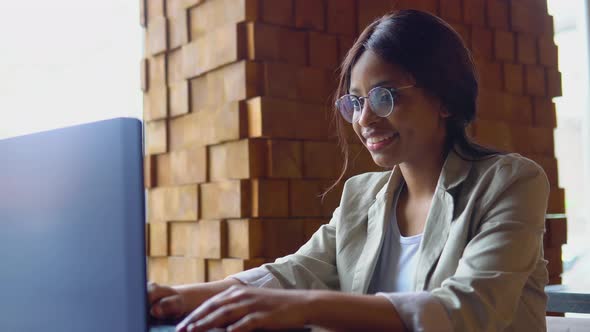Smiling Young Indian Woman Blogger Influencer Sit in Cafe Working on Laptop alt