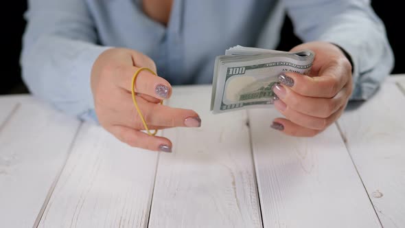 A Woman Tying a Stack of Hundreddollar Bills with a Rubber Band for Money alt
