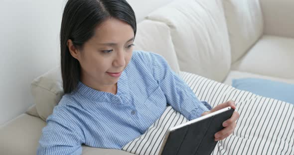 Woman Look at Tablet Computer and Sit on Sofa at Home