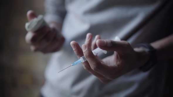 Unrecognizable Teenager Holding Syringe and Pack of Dollars in Hands. Young Mixed-race Boy with alt