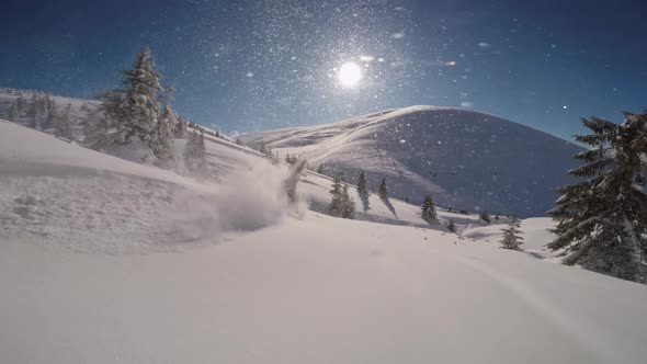Snowboarder Jumps on a Bump in Freeride with Sun in the Shot and Snow Shining in the Air alt