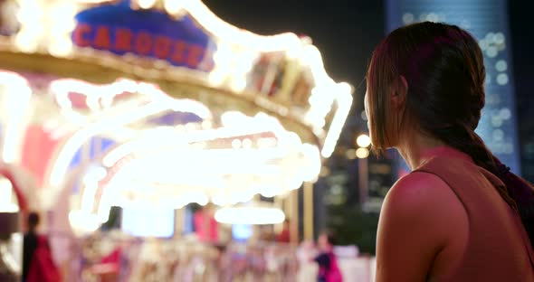 Woman taking photo and video in amusement park at night alt