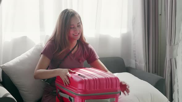 Cute woman happily zipping a suitcase smiling with her passport and credit card alt