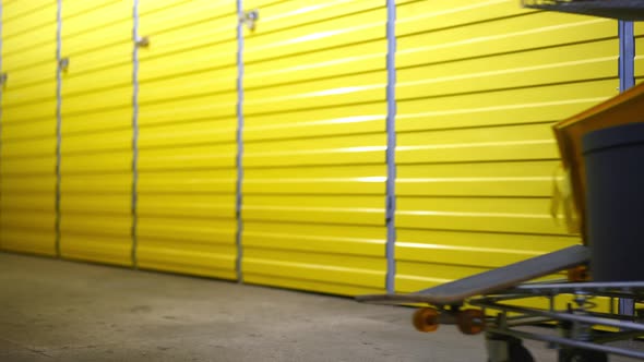 Row of Yellow Storage Rooms Doors with Legs of Young Woman Passing Pushing Trolley alt