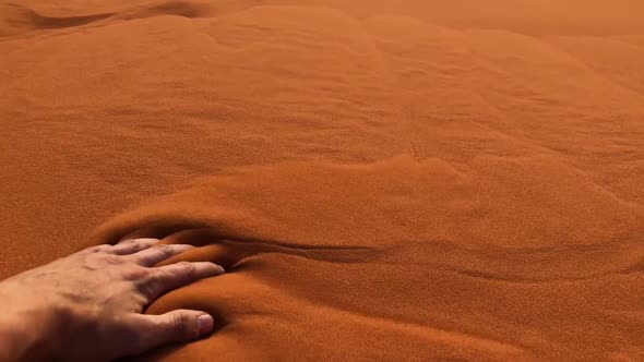 Slow motion shot of a man's hand moving through sand in the Wadi Rum Desert, Jordan. alt