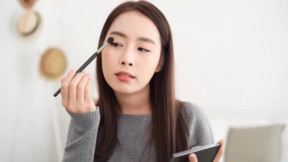 Young beautiful Asian woman professional beauty influencer doing cosmetic makeup tutorial online