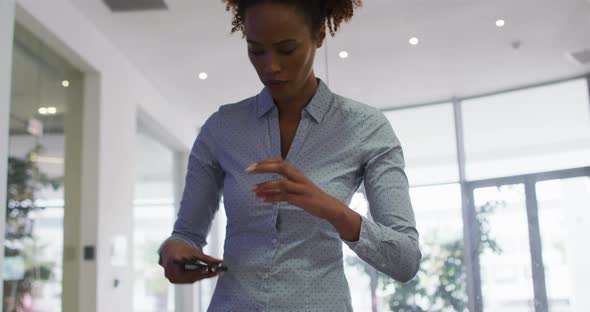 Mixed race businesswoman taking photos with smartphone in office alt