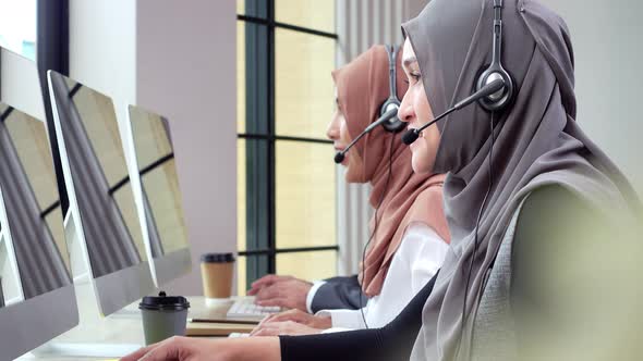 Asian mulsim customer service team talking on microphone headset working in call center