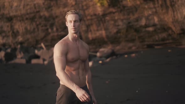 Athletic Caucasian Man Walking Topless on the Seashore After Workout alt